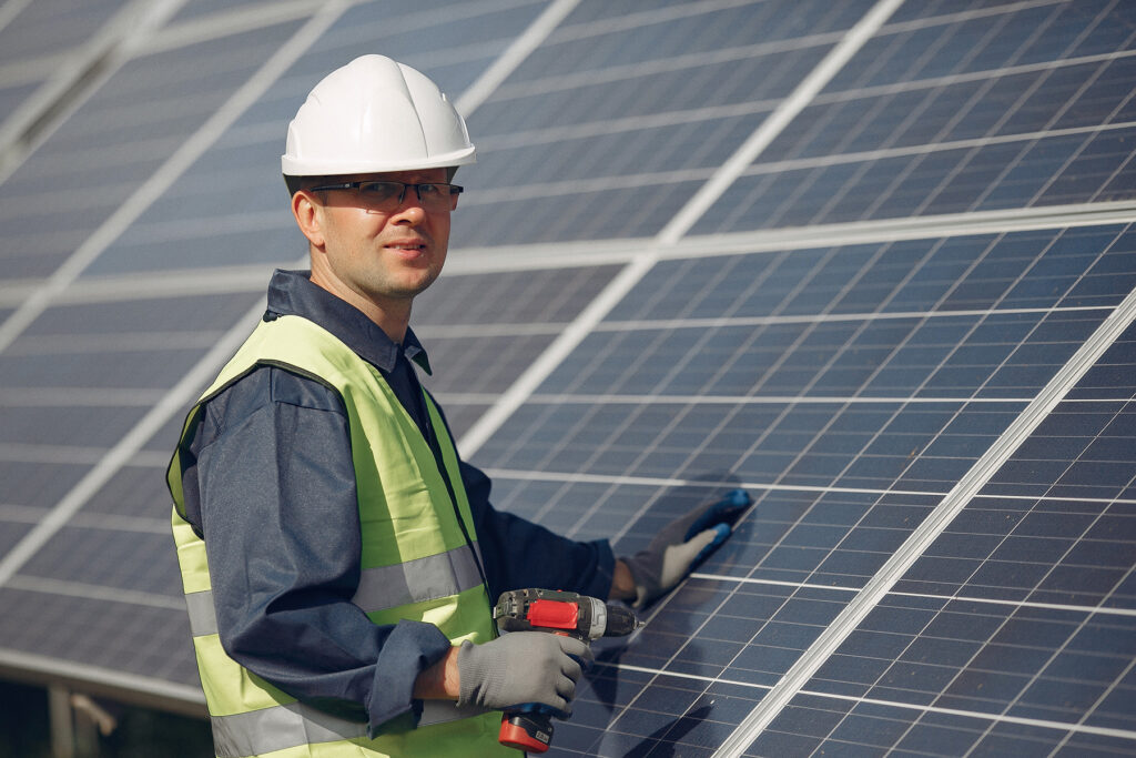man in a white helmet near a solar panel
